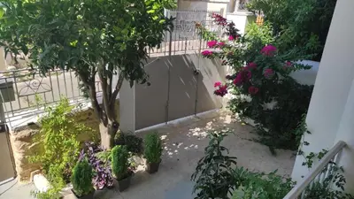 a courtyard with a tree and some flowers at Comfortable Apartment Close to the Airport in Spáta