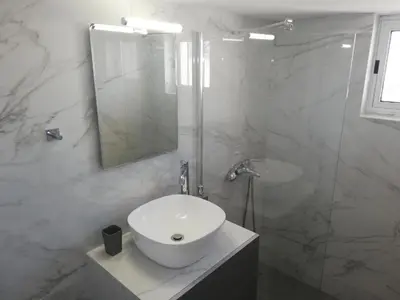 a white bathroom with a sink and a shower at Comfortable Apartment Close to the Airport in Spáta