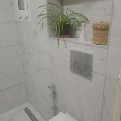 a white bathroom with a toilet and a plant at Socrates path in Athens