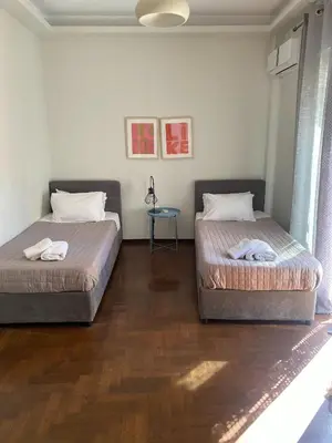 two beds in a bedroom with a wooden floor at MUSE A Dreamy and Fresh New apartment in Athens
