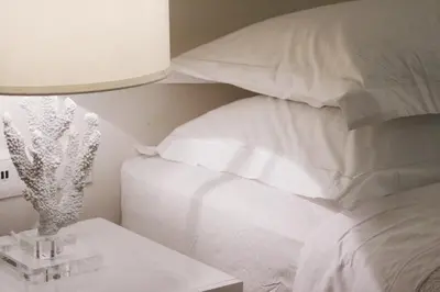 a bed with white pillows and a table with a lamp at Acropolis TownHouseCo Suites in Athens