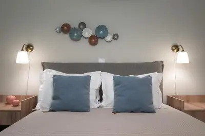 a bedroom with a bed with blue pillows and two lights at Absolute Athens ΙΧ in Athens