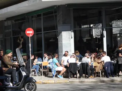 a crowd of people sitting at tables in front of a building at Koukaki-comfy with a balcony apt. in Athens