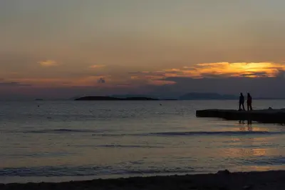 two people standing on the beach at sunset at Amazing Seafront Apartment Athens Riviera in Athens