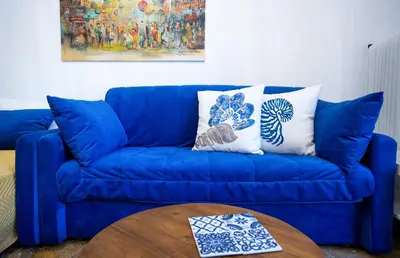 a blue couch with two pillows and a table at Unique apartment in Glyfada center in Athens