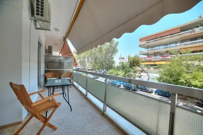 a balcony with a chair and a table and a train at Unique apartment in Glyfada center in Athens