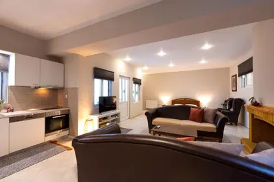 a living room with a couch and a table and a kitchen at Emma's Airport Studio in Spáta