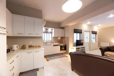 a kitchen and living room with white cabinets and a couch at Emma's Airport Studio in Spáta