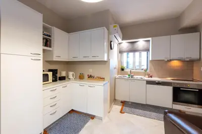 a kitchen with white cabinets and a white refrigerator at Emma's Airport Studio in Spáta