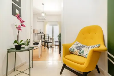 a living room with a yellow chair and a table at Athena by Heloni Apartments in Athens