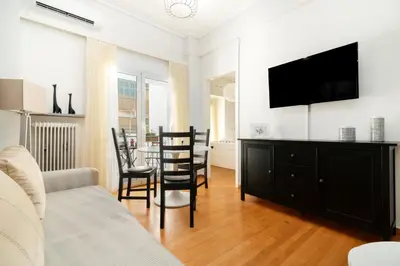 a living room with a tv and a table with chairs at Athena by Heloni Apartments in Athens
