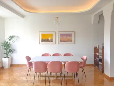 a dining room with a white table and pink chairs at Athens Heritage Suite in Athens