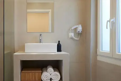 a bathroom with a sink and a mirror and towels at Athenian Sensations Apartments and Suites in the Heart of Athens in Athens
