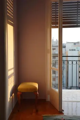 a yellow stool sitting in front of a window at Vintage, spacious apartment in the heart of Athens! in Athens