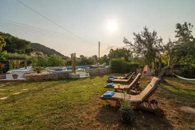 a row of lounge chairs in a yard with a pool at Spa Villa34 Family resort Renew, Relax, Revitalise in Aghia Marina