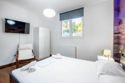 a white bedroom with a bed and a chair at Spa Villa34 Family resort Renew, Relax, Revitalise in Aghia Marina
