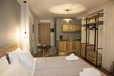 a bedroom with a large white bed and a kitchen at 2the Point Athens Suites & Appartments in Plaka in Athens