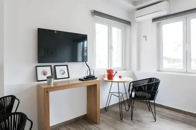 a living room with a table and chairs and a tv at CosmosDome. Best view in the heart of Athens! in Athens