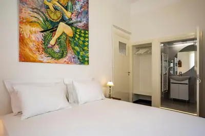 a bedroom with a white bed with a painting on the wall at Delightful 2 BEDR-2 BATH Apt with Access to Rooftop Garden - EP9U in Athens