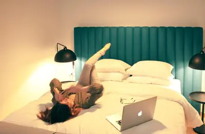a woman laying on her back on a bed with a laptop at Athens Blossom House under Acropolis with private entrance in Athens