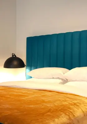 a bed with a blue headboard and white sheets and pillows at Athens Blossom House under Acropolis with private entrance in Athens
