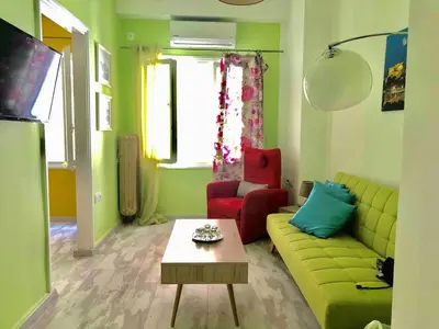 a living room with a green couch and two red chairs at Athens historical center Love suite 2 in Athens