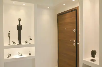 a hallway with a wooden door and shelves with figurines at Athens historical center Love suite 2 in Athens
