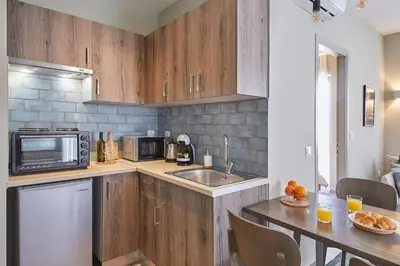 a kitchen with wooden cabinets and a sink and a table at Spacious Suite w. huge balcony + Acropolis view in Athens