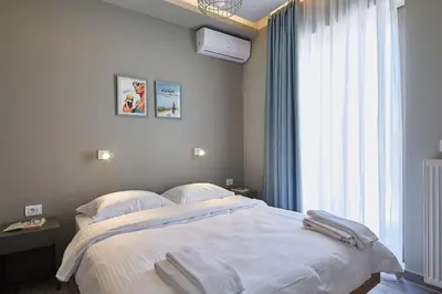 a bedroom with a bed with white sheets and a window at Spacious Suite w. huge balcony + Acropolis view in Athens