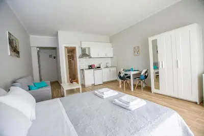 a white bedroom with a white bed and a kitchen at Raise comfy studios in the heart of Athens in Athens