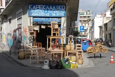 a building with wooden chairs and tables on a street at Enticing, Cosy, Rooftop Studio Athens Centre! EP9T in Athens