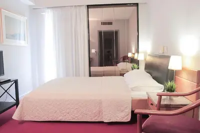 a bedroom with a white bed and a living room at Hotel Victory in Athens