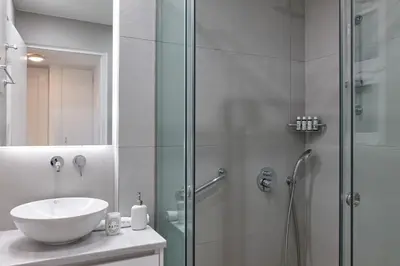a bathroom with a sink and a glass shower at Chic One Bd Apartment with Hilton View in Athens