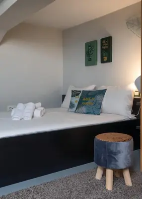 a bed with white sheets and pillows and a stool at Athens Downtown Loft in Athens