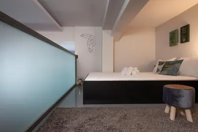 a bedroom with two beds and a stool in a room at Athens Downtown Loft in Athens