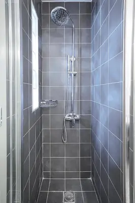 a bathroom with a shower with black tiles at Walk through Athens from 1-bdr next to Acropolis! in Athens