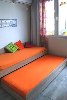 two twin beds in a room with orange sheets at Sunny studio with Parthenon view balcony in Athens