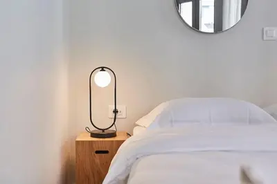 a bedroom with a bed and a lamp on a night stand at Explore Athens from an uber-central studio! in Athens