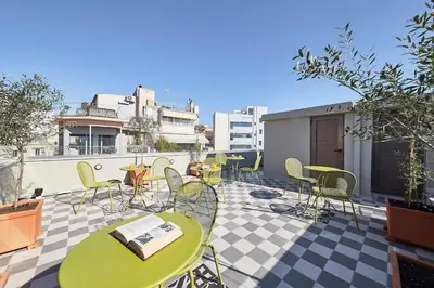 a patio with tables and chairs on a roof at Explore Athens from an uber-central studio! in Athens