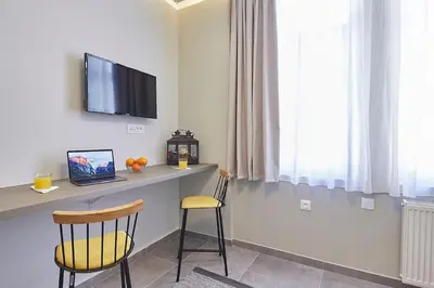 a room with a desk with a television and two chairs at Old Athens style 1bdr with Acropolis view rooftop! in Athens