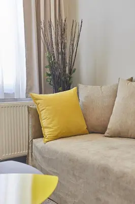 a yellow pillow on a couch in a living room at Old Athens style 1bdr with Acropolis view rooftop! in Athens