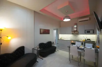 a living room with black furniture and a kitchen at ARETI in Athens