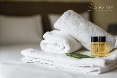 a pile of towels and a bottle of essential oil on a bed at Thresh Apartments Airport by Airstay in Spáta