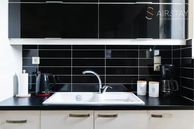 a kitchen with a sink and a black tiled wall at Thresh Apartments Airport by Airstay in Spáta
