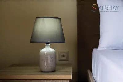 a lamp sitting on a table next to a bed at Thresh Apartments Airport by Airstay in Spáta