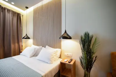 a bedroom with a bed with white sheets and a plant at Still Athens in Athens