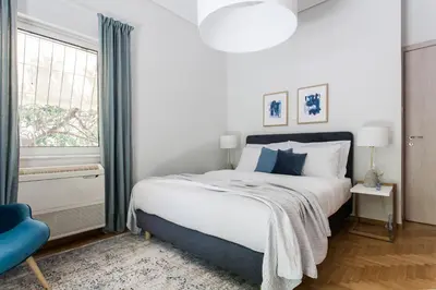 a bedroom with a large bed and a blue chair at Bright 2BD Apartment in Psychiko by UPSTREET in Athens