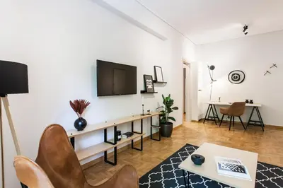 a living room with a tv and a table at Bright 2BD Apartment in Psychiko by UPSTREET in Athens