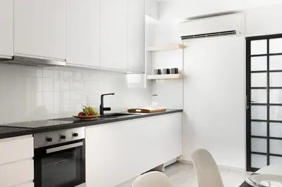 a white kitchen with white cabinets and black counter tops at Athens View Loft 07 & 08 in Athens