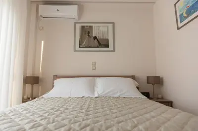 a white bed in a white bedroom with two lamps at ivannas penthouse in Athens